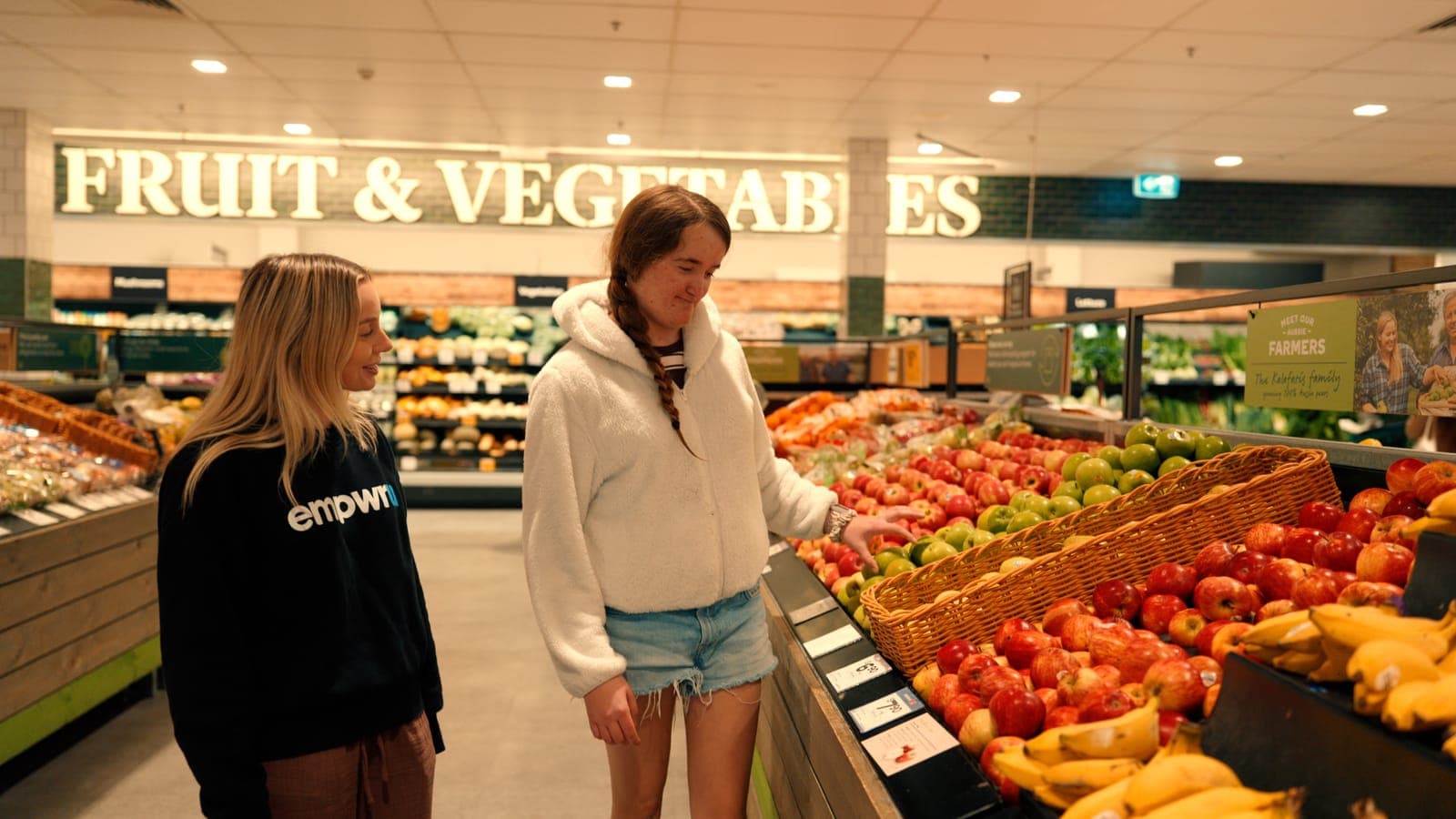 A participant choosing fruit at the supermarket with her EmpwrU support worker
