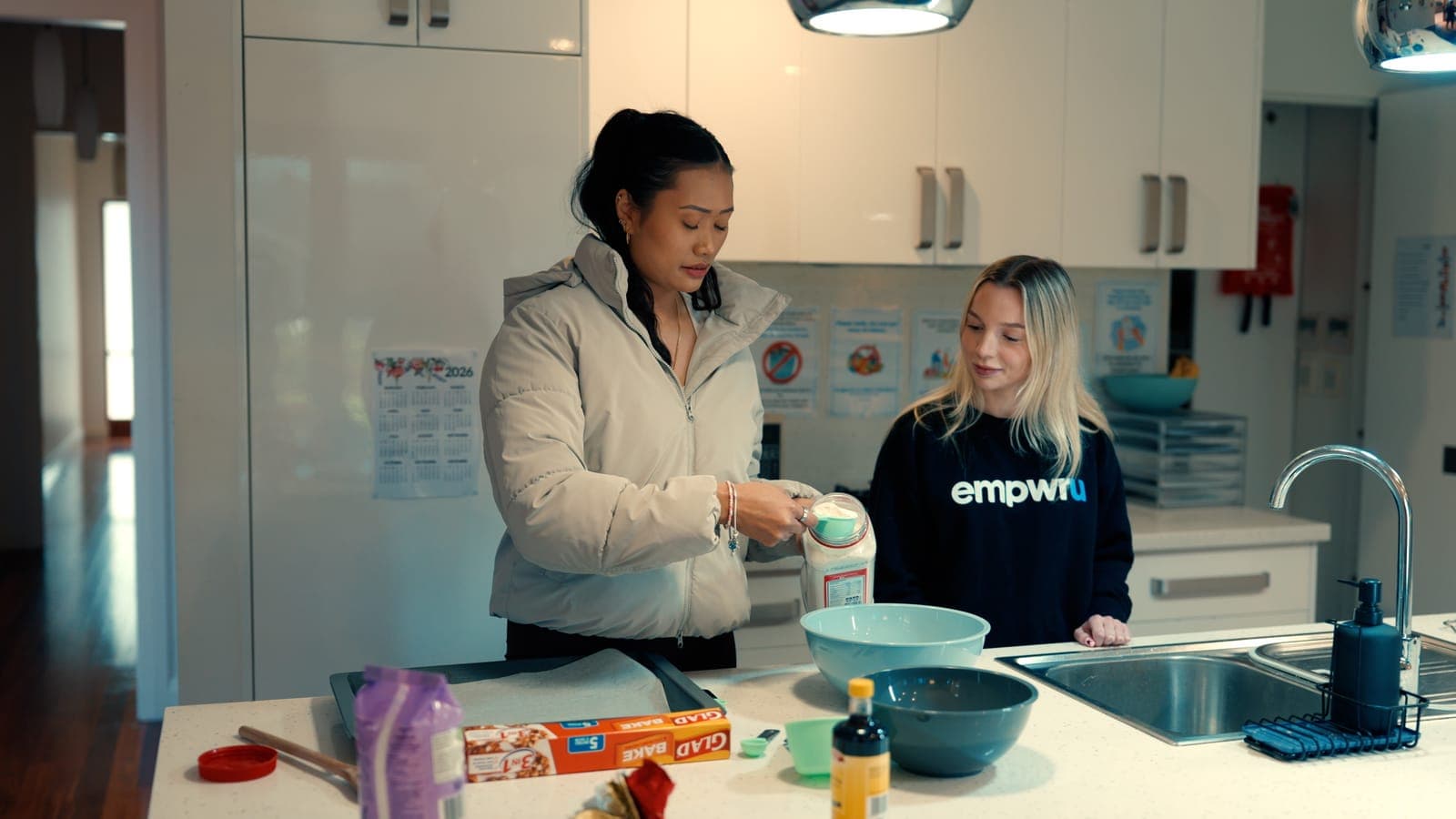 A participant measuring out ingredients in the kitchen with her EmpwrU support worker