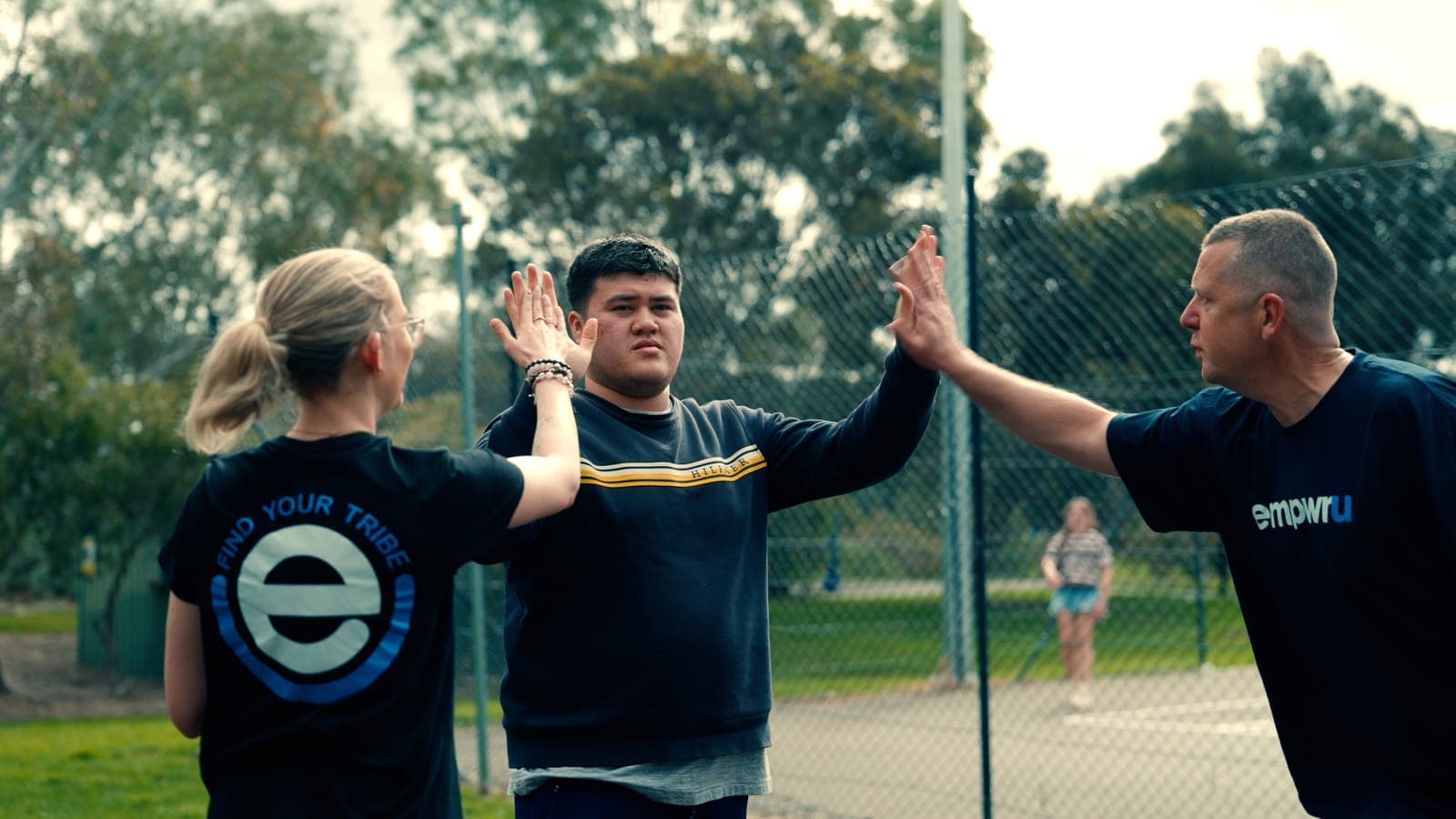 A participant high-fiving two EmpwrU support workers on the court
