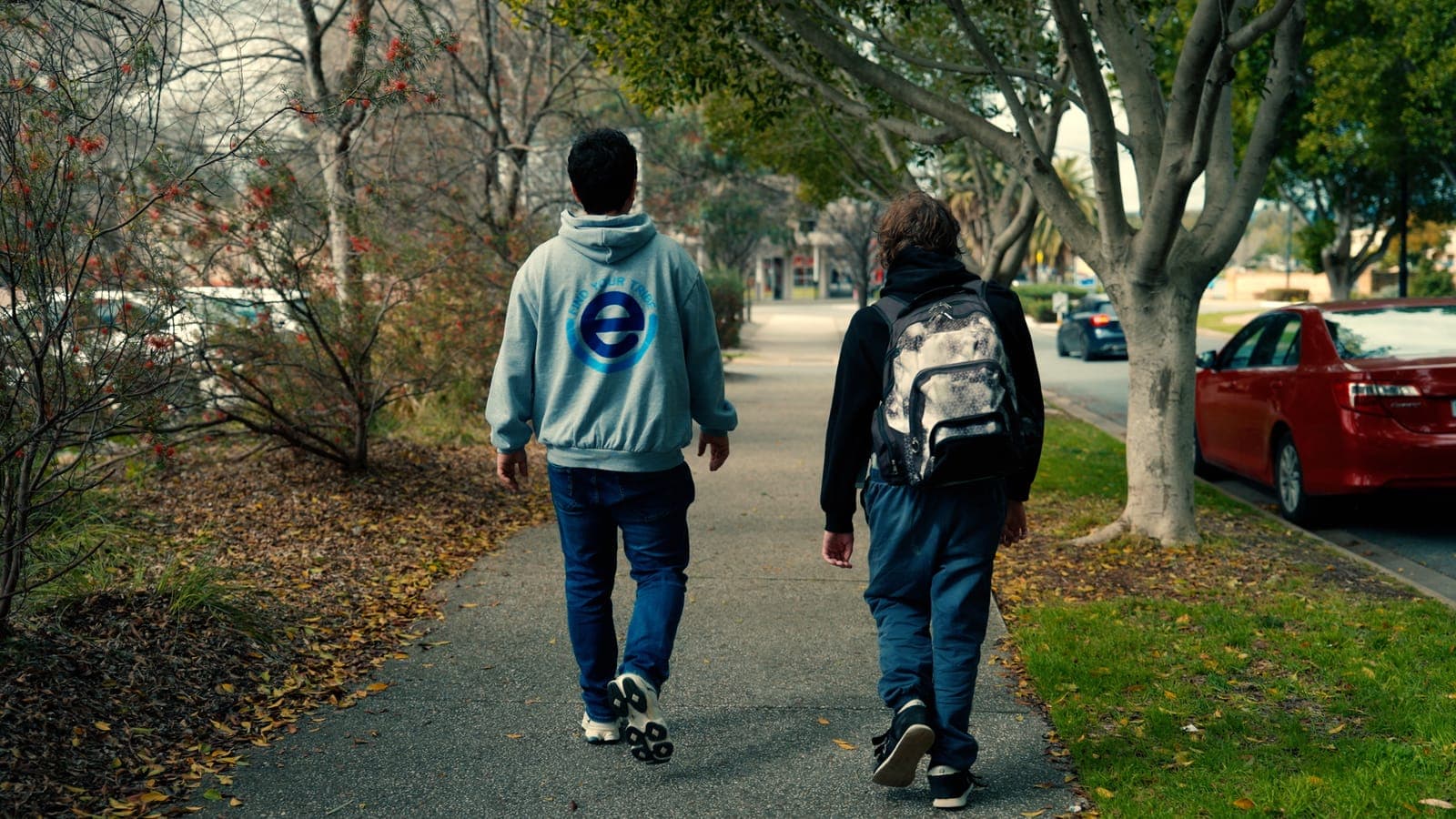 Two people walking down a suburban footpath, one in an EmpwrU Find Your Tribe hoodie